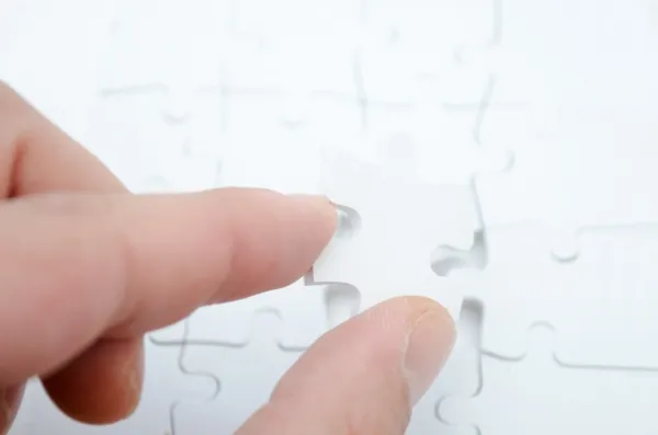 Social intranet adoption - person placing a white jigsaw puzzle piece to complete a puzzle