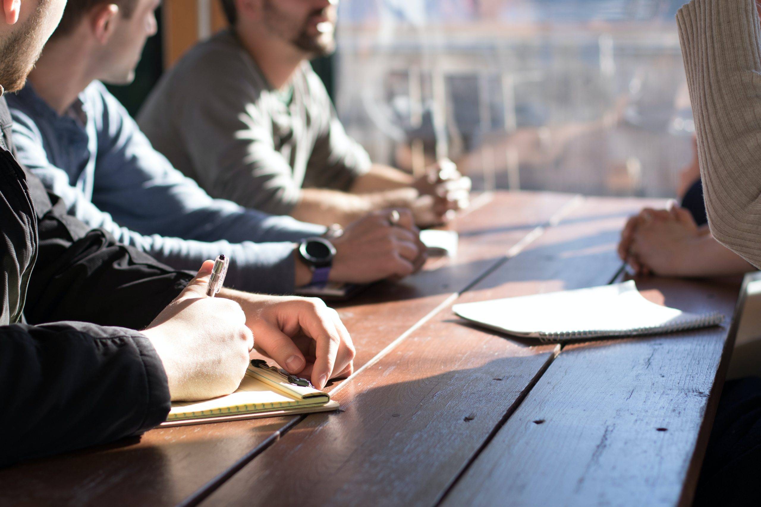 Traits of a good leader: a group of employees sitting around a table, actively engaged in discussion