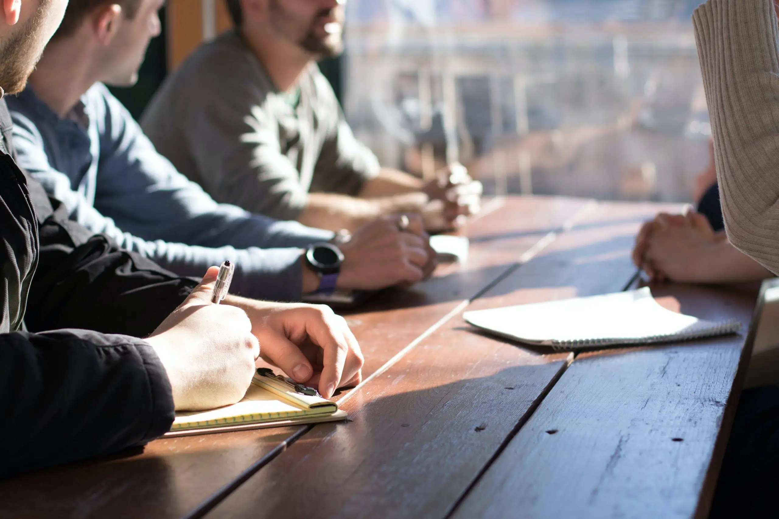 Traits of a good leader: a group of employees sitting around a table, actively engaged in discussion