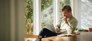 Man in glasses using laptop while sitting at table