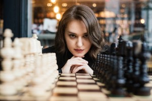 A woman playing chess to demonstrate navigating the emotional and behavioral components of employee engagement