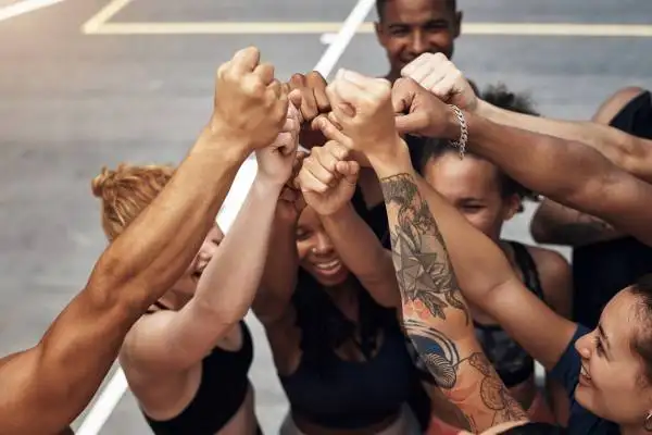 Employee engagement - a group of employees raising hands up to demonstrate the power of teamwork