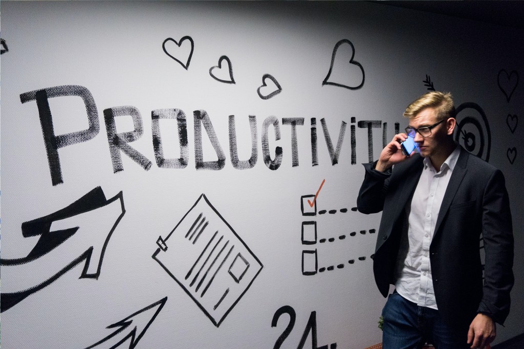 Employee talking on a cell phone next to a wall with the word productivity on it