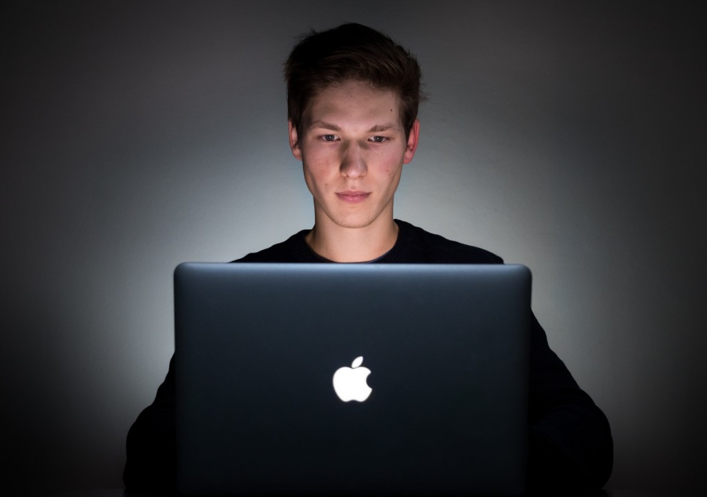 Employee onboarding - man using Apple laptop in a darkened room
