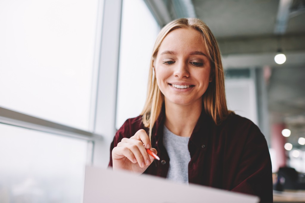 Employee onboarding - smiling blonde woman working on her laptop computer