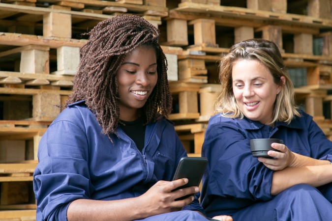 Internal comms - female factory workers smiling and looking at smartphone