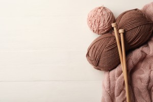 Woolen,Yarns,,Knitting,Needles,And,Sweater,On,White,Wooden,Background,