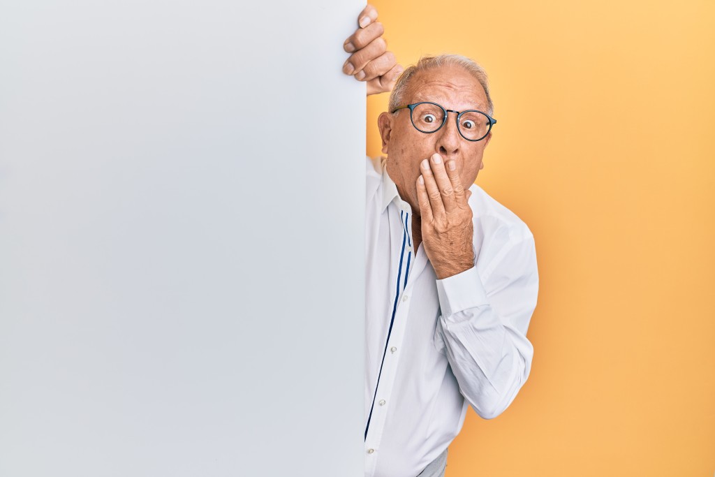 Salary discussion a taboo? - older man leaning around a wall, looking shocked, and covering his mouth