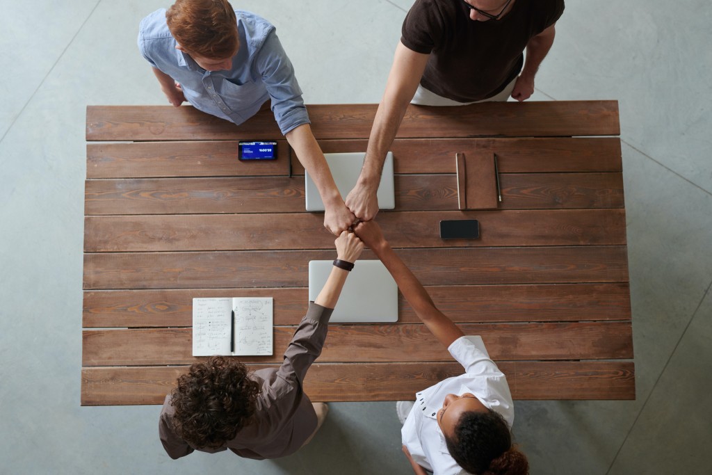 Employee experience team of four people fistbumping