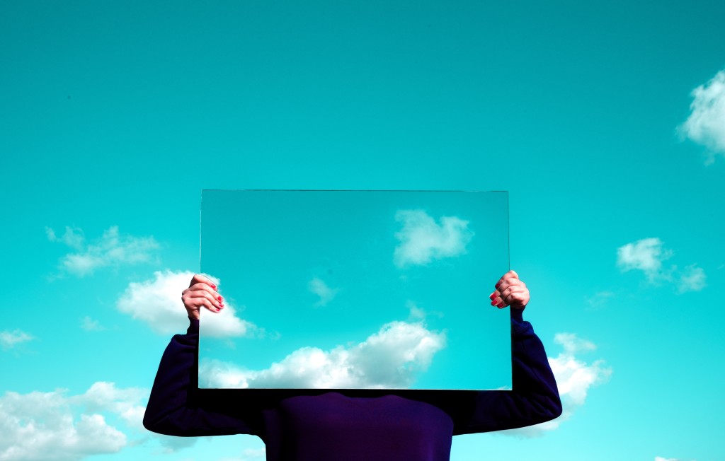 Salary talk and quiet quitting - person holding mirror in front of face to reflect the sky