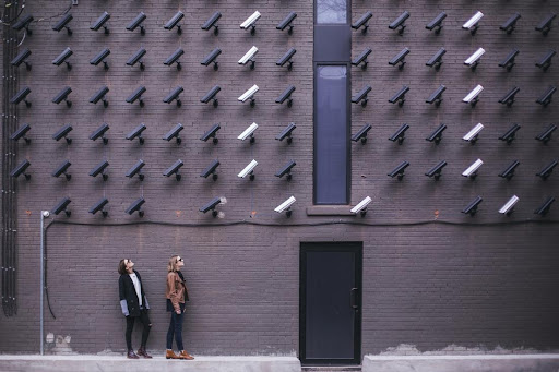 Two employees looking up at security cameras on a public building
