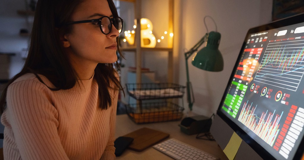 Equitable EX - female employee with glasses working at desktop looking at screen with multiple graphs