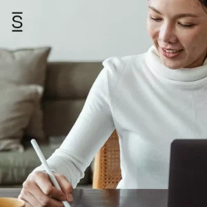 Work From Home - woman writing on unseen notepad while computer sits in front of her