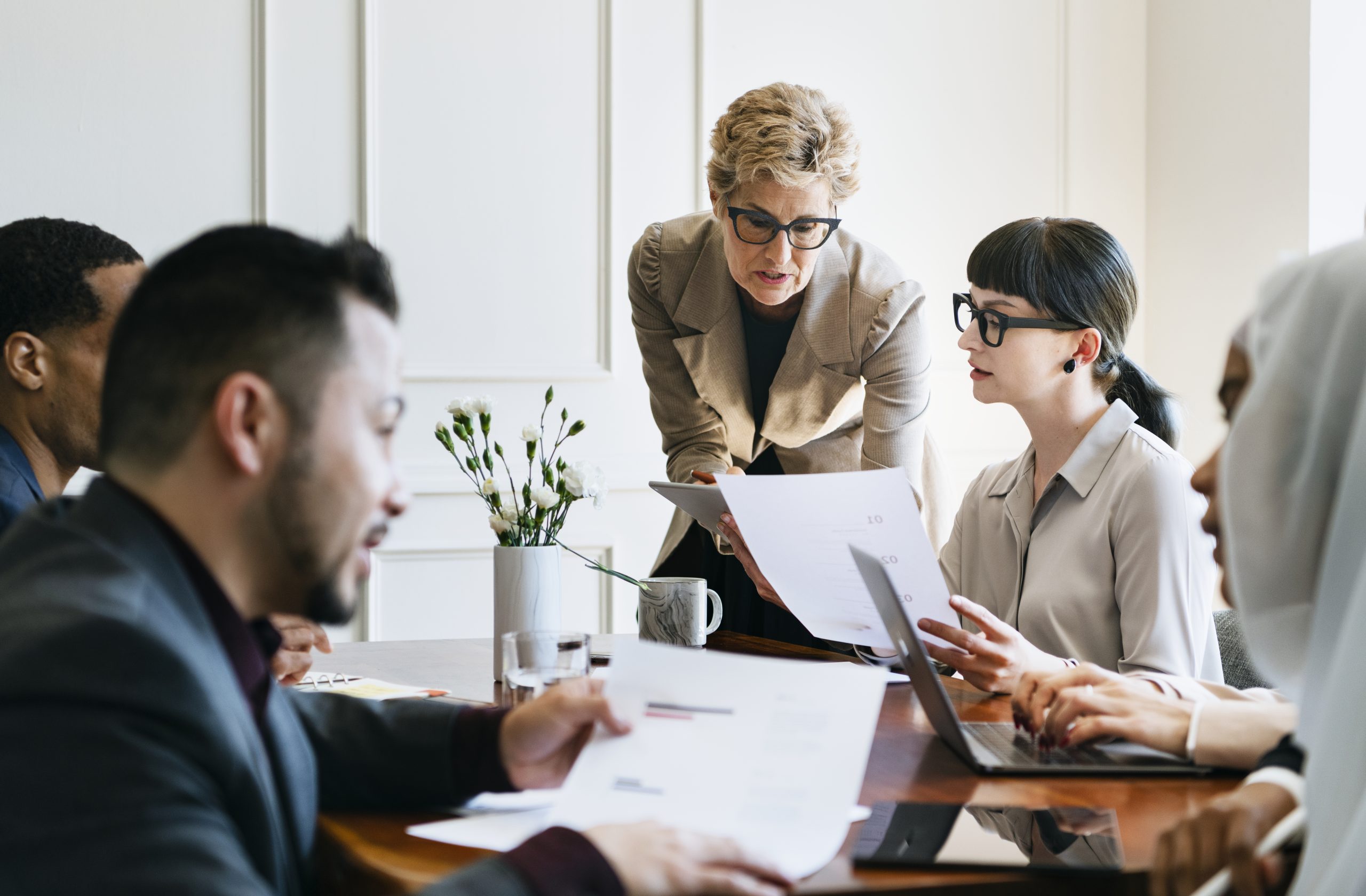Leadership: A good leader guiding a diverse team through documents and discussion during a collaborative meeting.