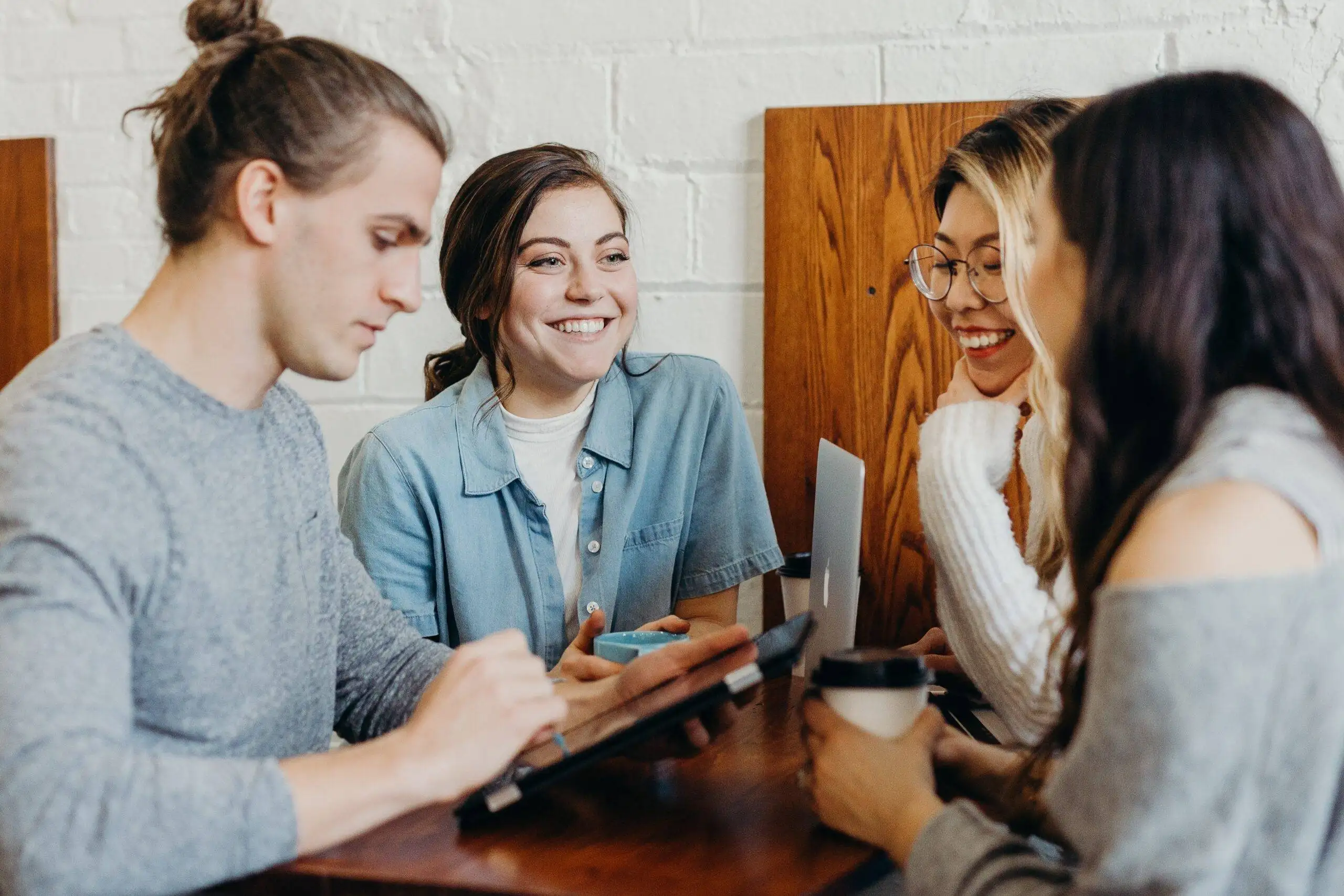A male colleague and three female colleagues are collaborating effectively, demonstrating the power of teamwork while sitting across from each other.