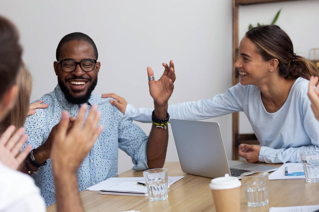 Employee engagement - group of employees congratulating one of their colleagues on a job well done
