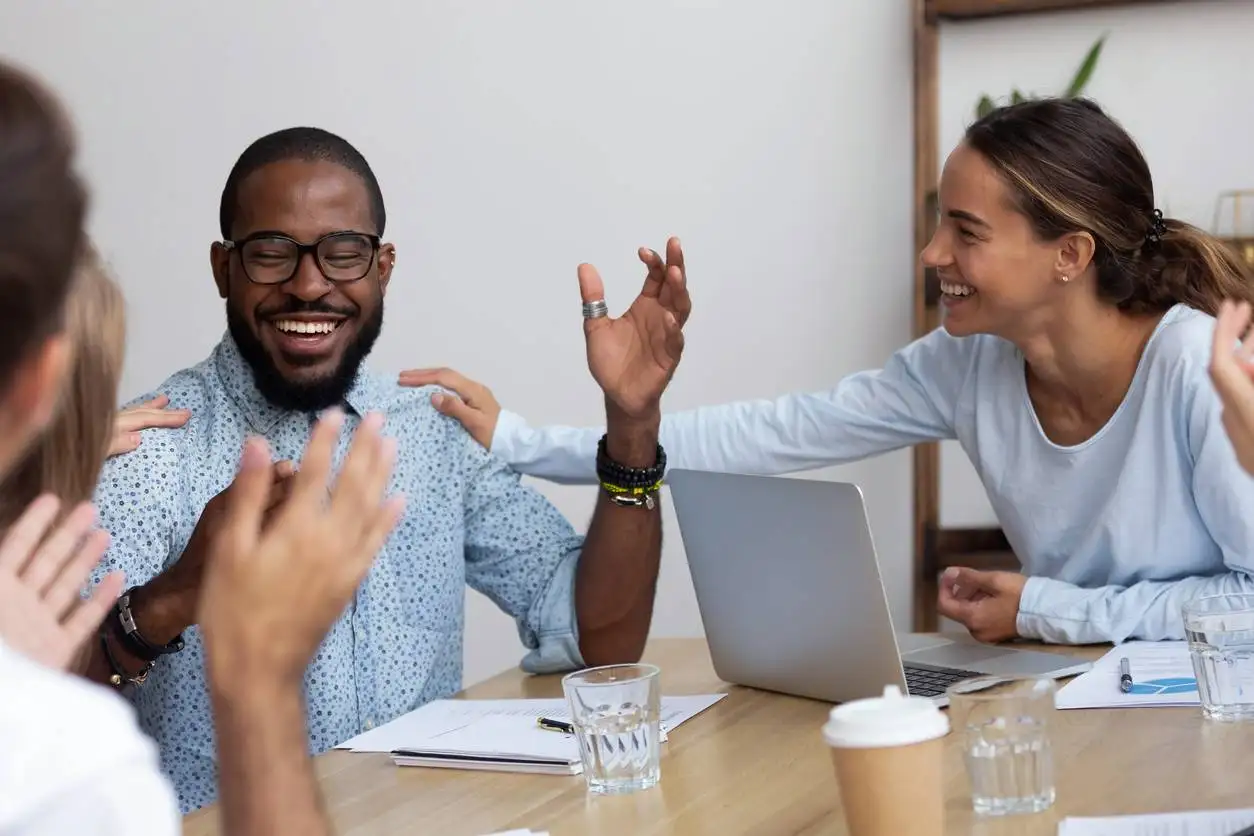 Employee engagement - group of employees congratulating one of their colleagues on a job well done