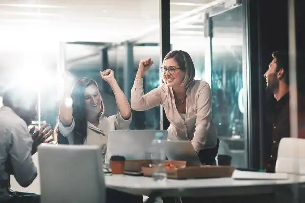 Employee onboarding - Shot of colleagues celebrating during a meeting in a modern office