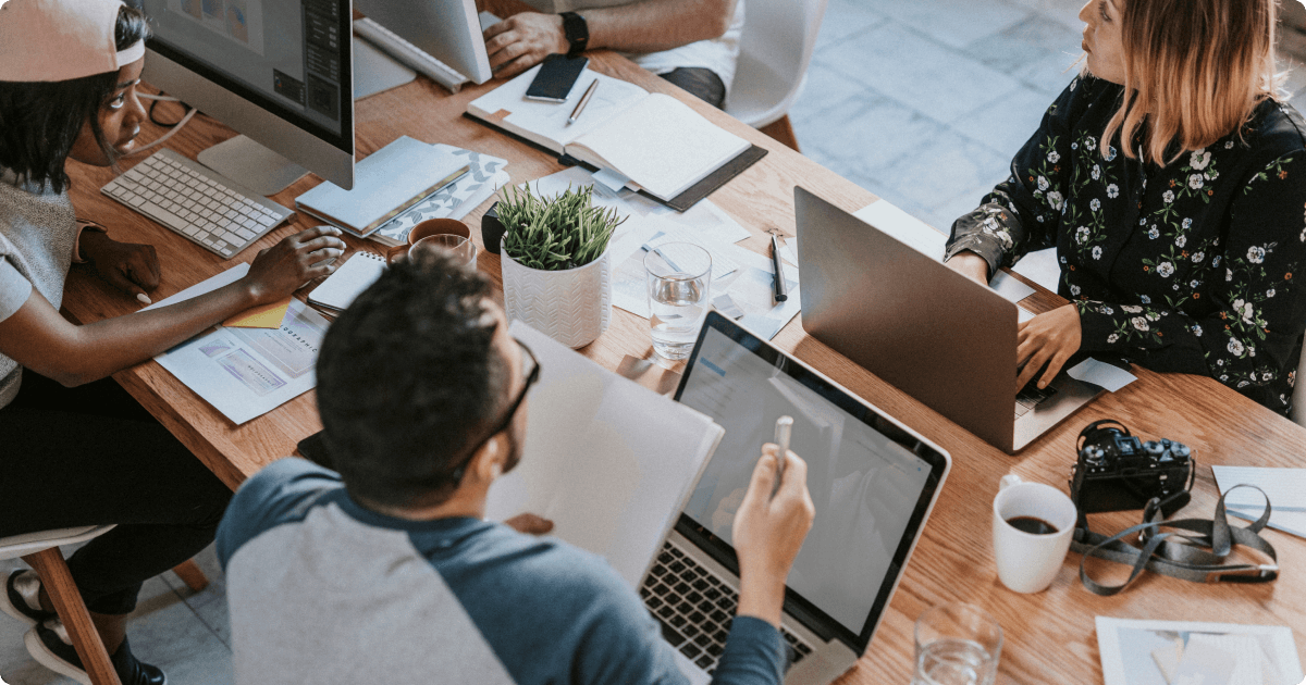 Best internal communication software: employees sitting around a table engaged in a team discussion