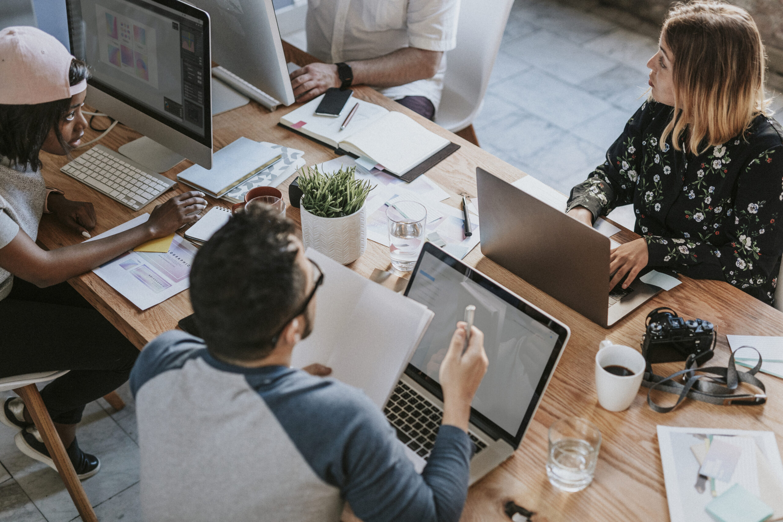 Prescriptive analytics: A group of employees sitting around a conference table, engaged in discussion and collaboration, reviewing data charts and digital dashboards.