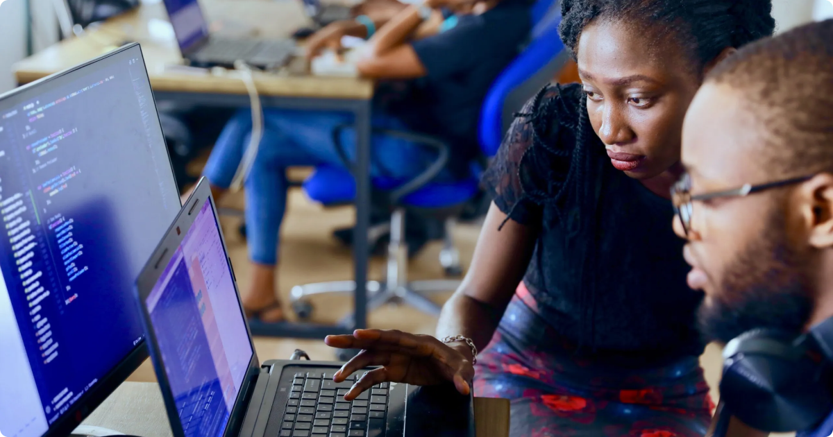 Learning management system (LMS): Two employees are working together on a laptop, engaging with an online training module in a collaborative workspace.