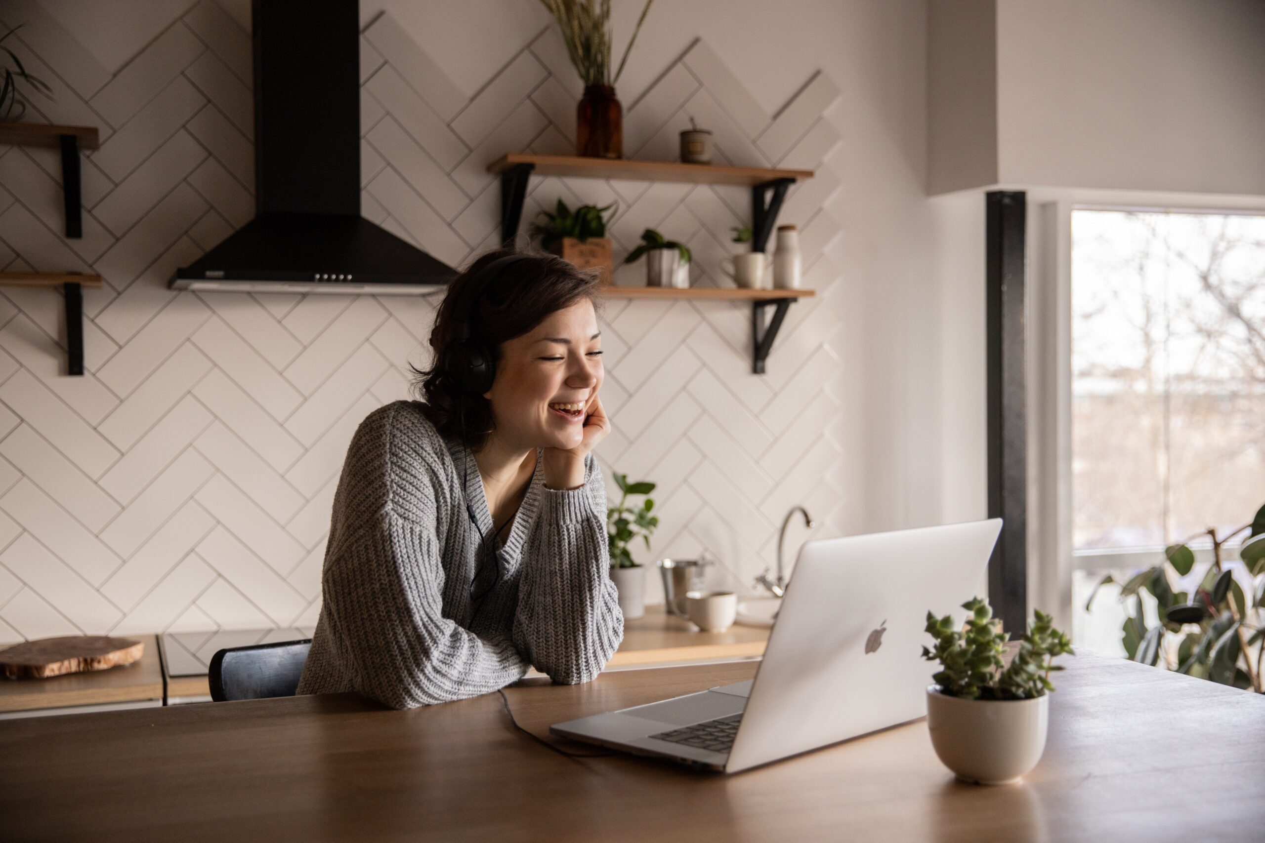 Benefits of remote working: Woman in a grey sweater is working from home on her laptop.