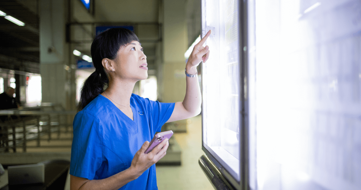 Simpplr and ScreenCloud: Frontline workers viewing company updates on large digital signage screens.