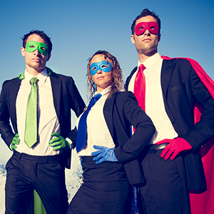 Two men & a woman in suit & tie and different colored capes and masks